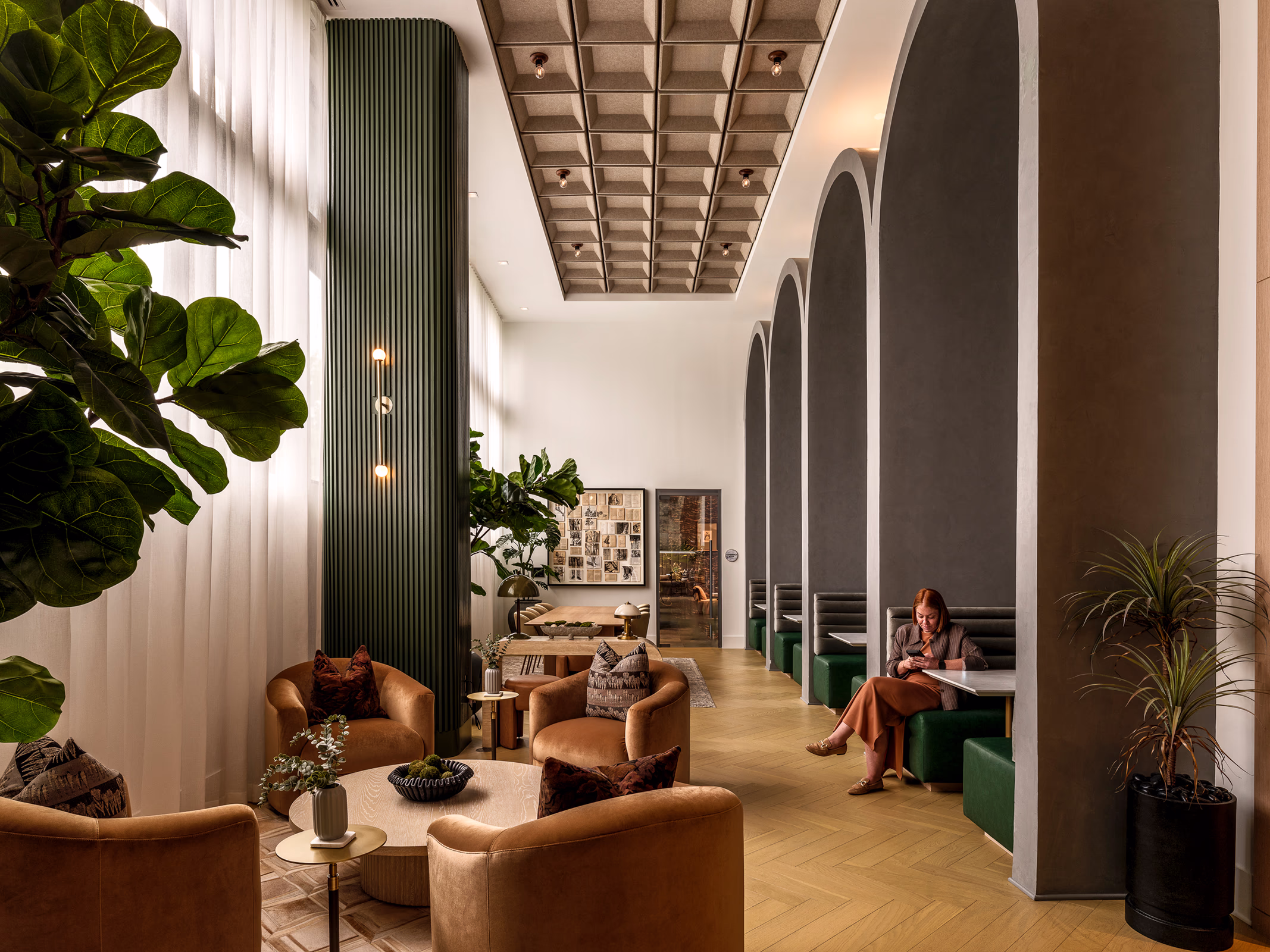 Modera Nations co-working space in Nashville with arched booth seating, velvet lounge chairs, a coffered ceiling and herringbone wood floors.