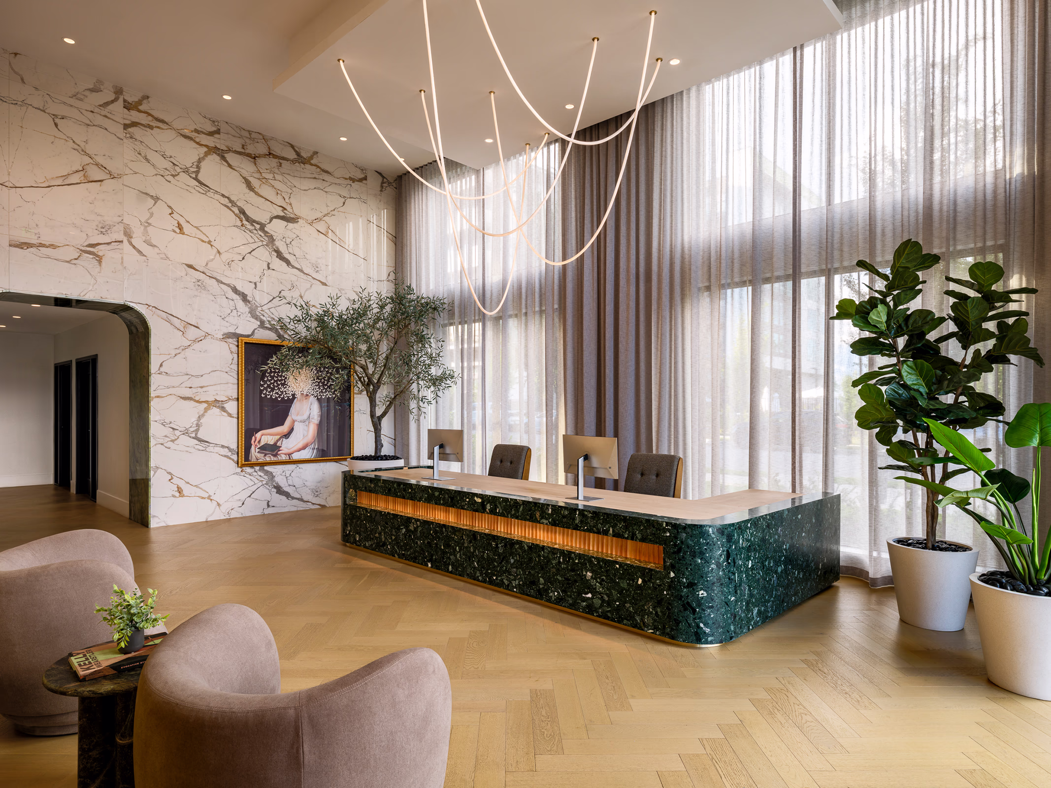 Modera Nations lobby in Nashville with a green terrazzo reception desk, veined marble wall, herringbone wood floors and a sculptural pendant light.