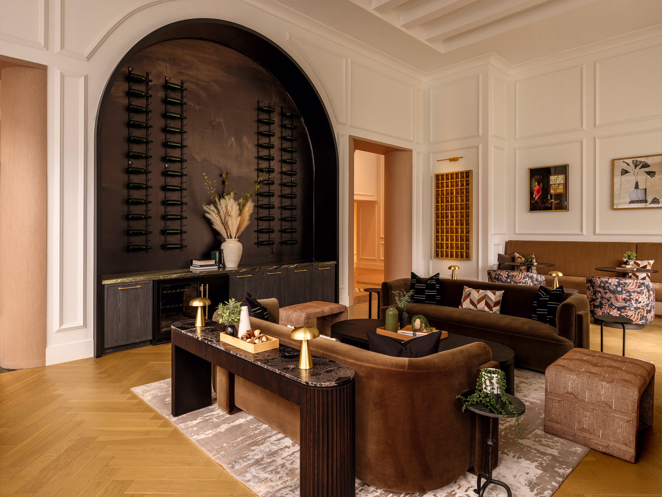 Modera Nations resident lounge in Nashville with an arched wine display wall, velvet sofas, herringbone wood floors and classic wall paneling.