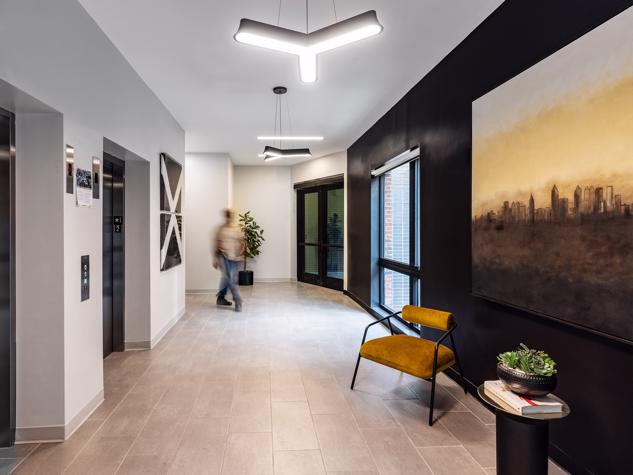 Front Porch Phase I lobby corridor with elevators, art, and Atlanta skyline painting, co-living residence