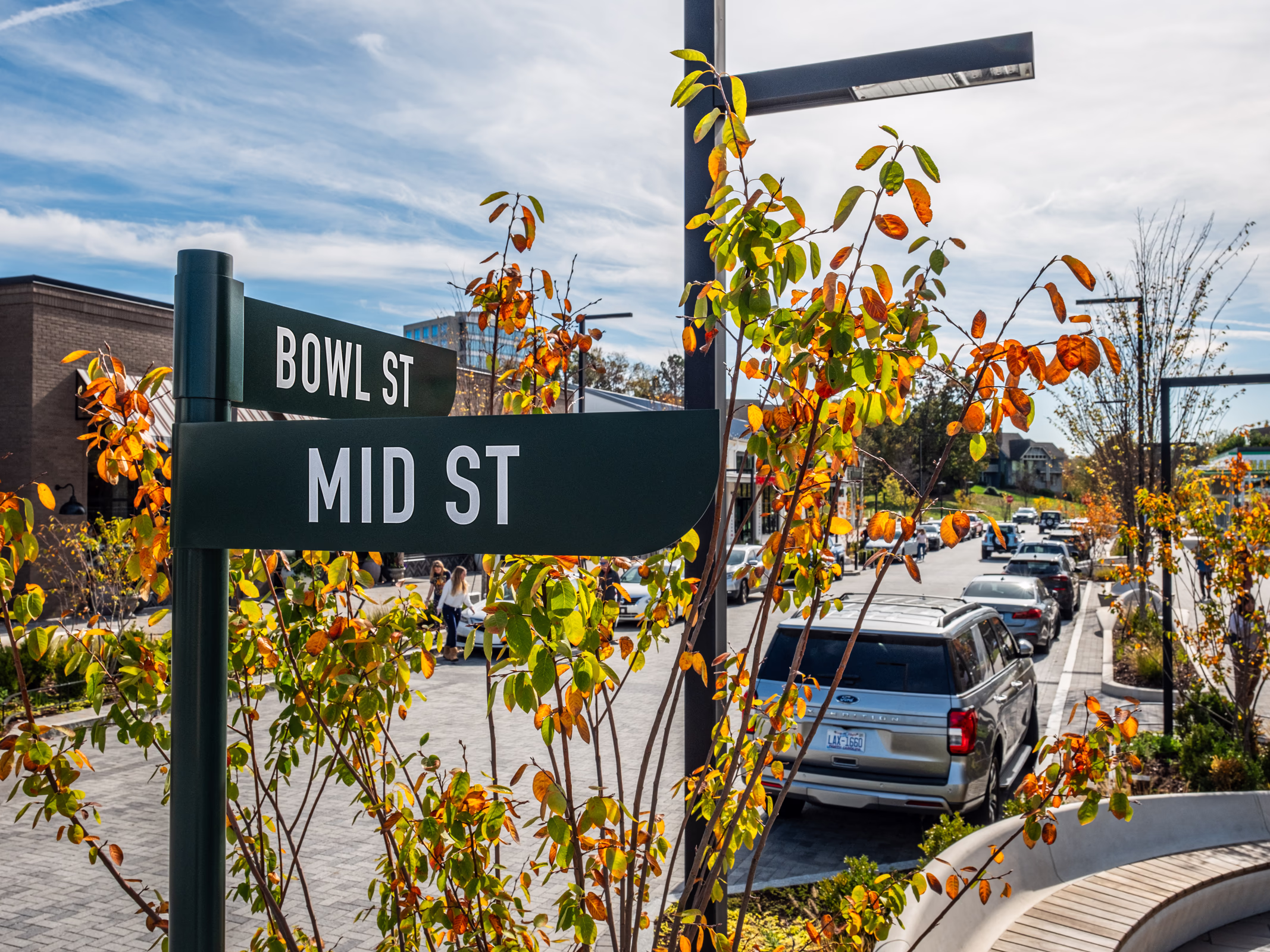 Bowl St and Mid St signs at The Bowl at Ballantyne in Charlotte, framed by fall foliage along a walkable main street with retail and parking.