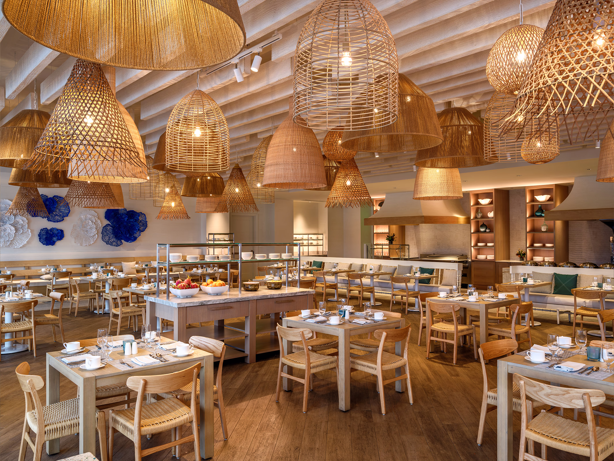 Shorebird restaurant dining room at Frenchman's Reef with woven rattan pendant lights, wood tables, and coral wall art.