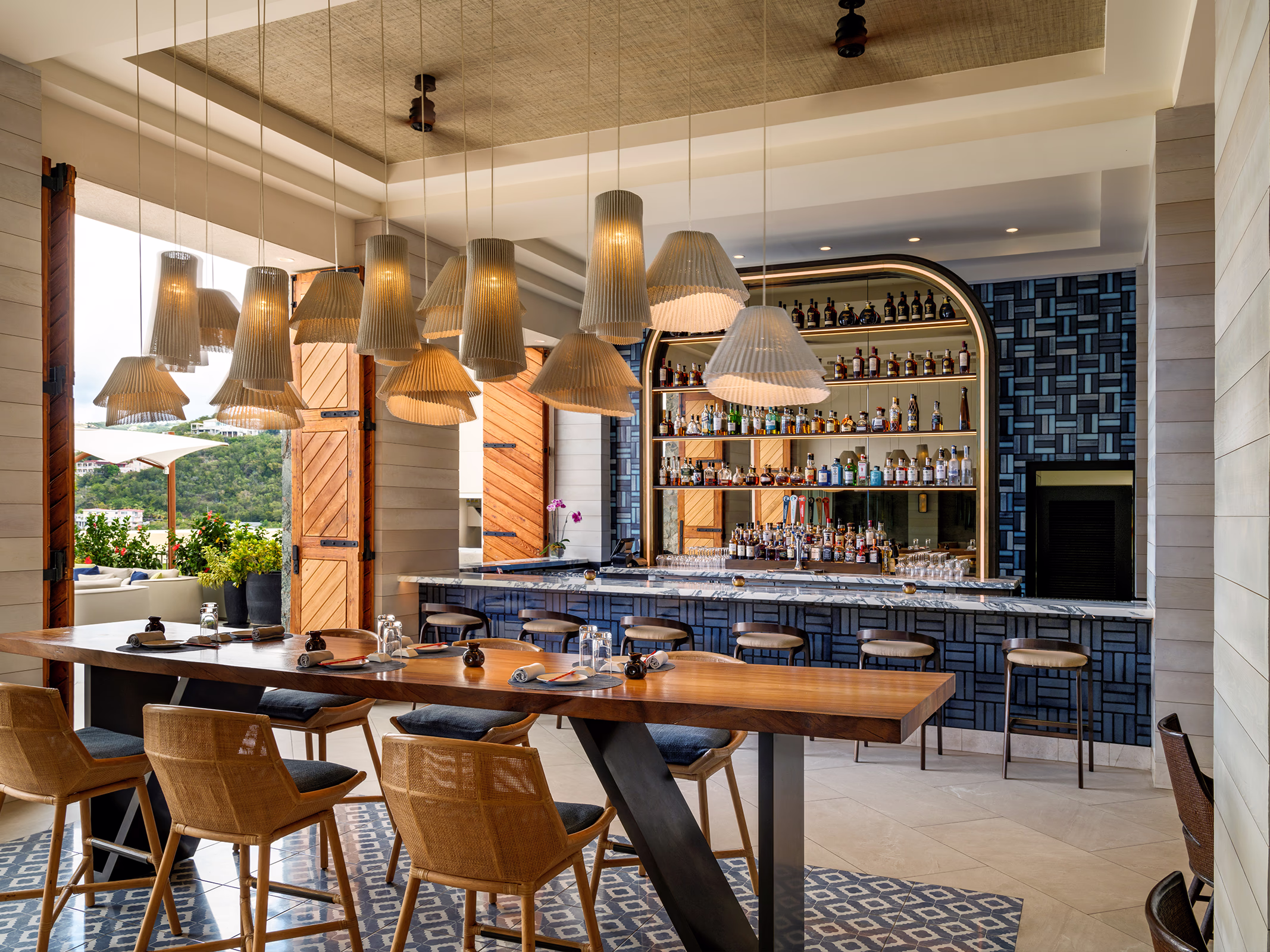 Sugarfin Rum Bar at Frenchman's Reef with a full spirits display, blue mosaic tile, and a communal wood table with island views.