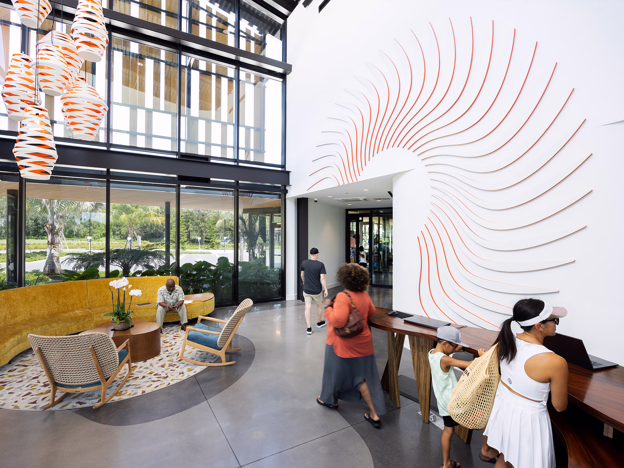 Sculpted white and orange sunburst feature wall rising above the check-in desk in the sunlit Evermore Orlando Resort lobby as guests arrive.
