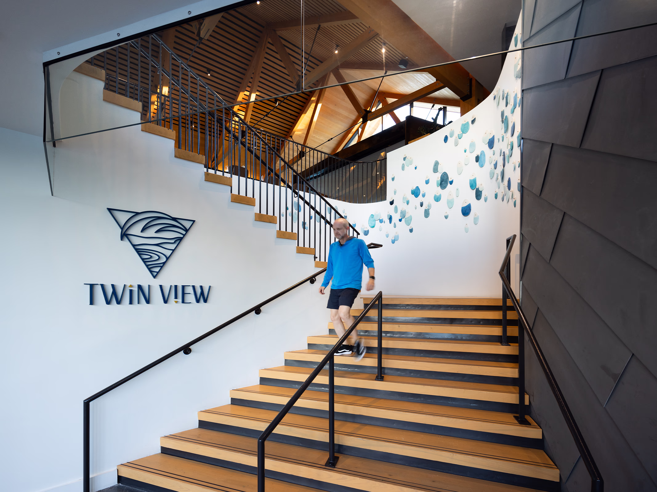 Dimensional navy Twin View logo sign in a timber stair hall at Evermore Orlando Resort, with a cascading blue ceramic art installation on the curved wall.