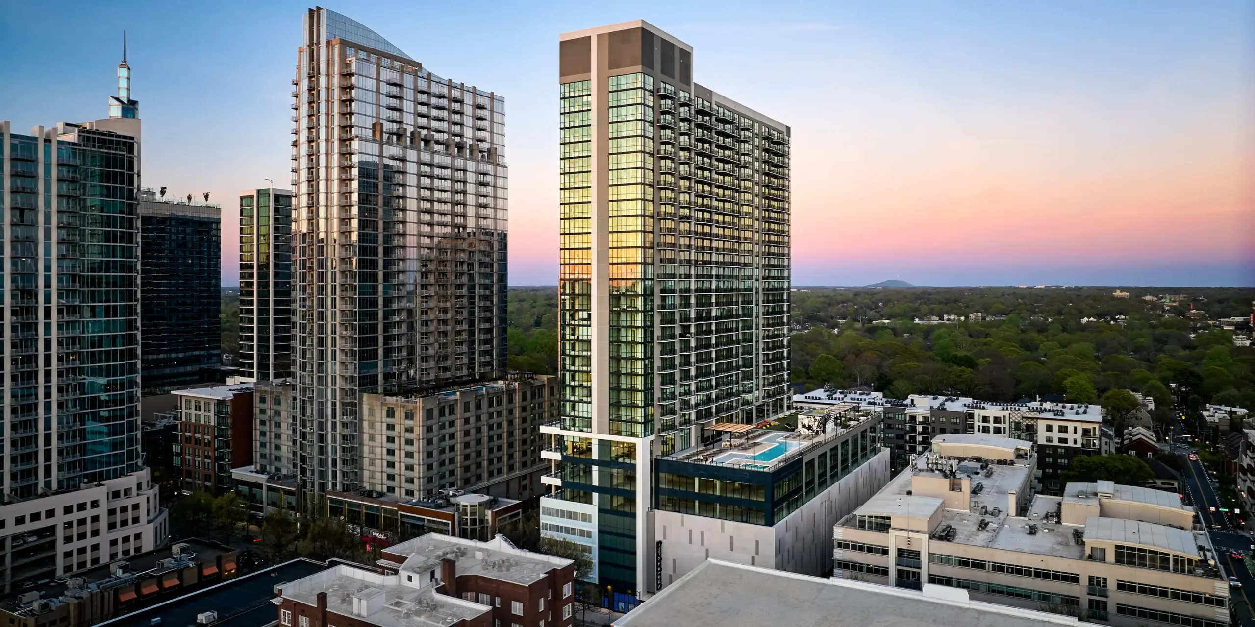 Dusk aerial view of Society Atlanta showing illuminated amenity deck and surrounding Midtown buildings
