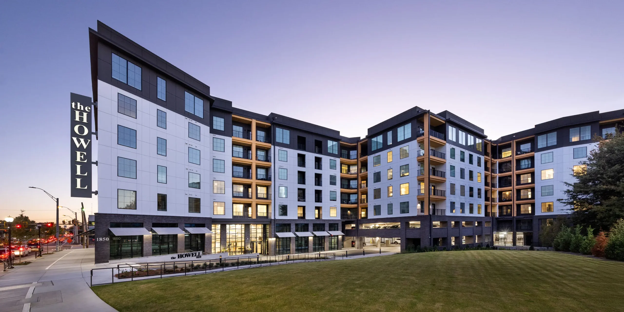 Nighttime street view of The Howell featuring the main entrance, parking access, and illuminated blade sign.