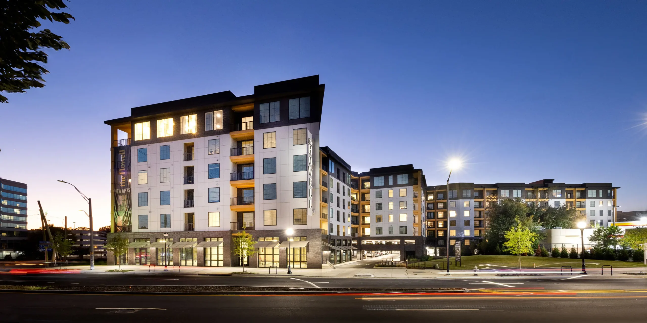 Nighttime street view of The Howell featuring the main entrance, parking access, and illuminated blade sign.
