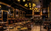 View from entrance of The Kennedy gastropub showing layered interior design, amber lighting, and bar framed by rich materials