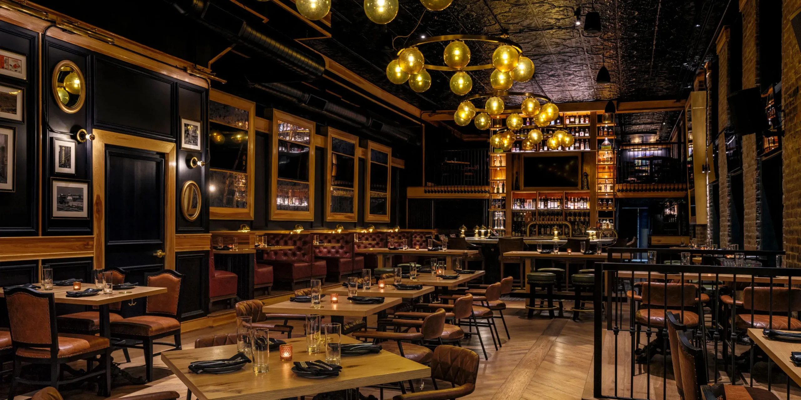 View from entrance of The Kennedy gastropub showing layered interior design, amber lighting, and bar framed by rich materials