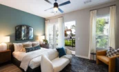 Bedroom interior at Pilot & Park apartments with large windows and city views.