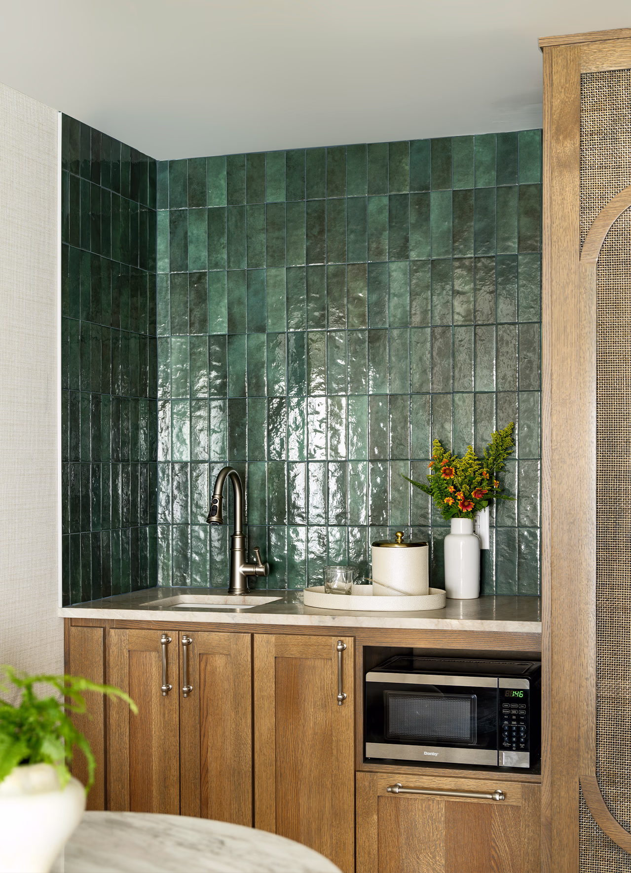 Suite kitchenette at The James F. Martin Inn with a glossy emerald tile backsplash, wood cabinetry, marble counter, and built-in microwave.