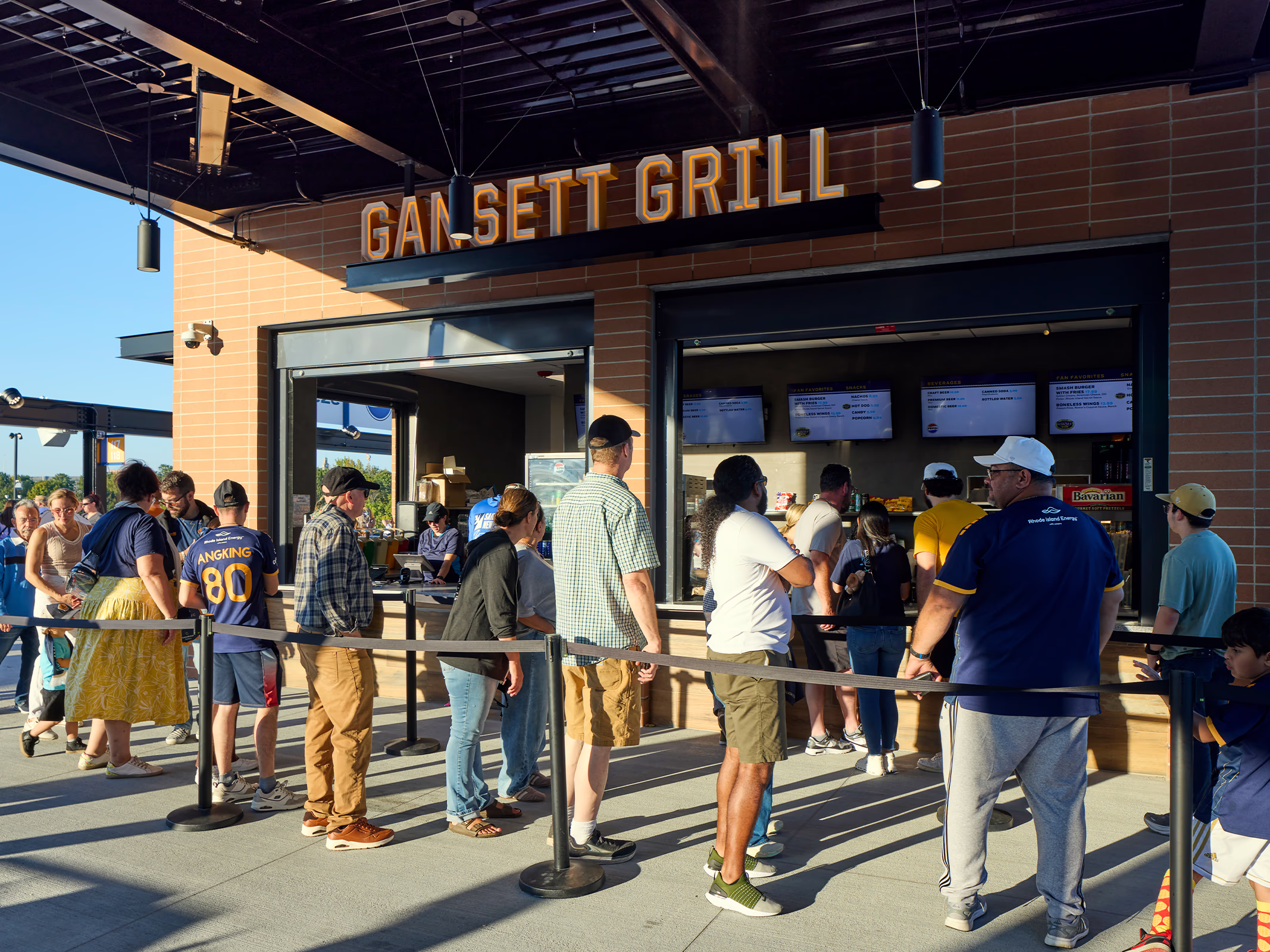 Dimensional Gansett Grill signage and digital menu boards brand a concession stand at Centreville Bank Stadium as fans line up to order.