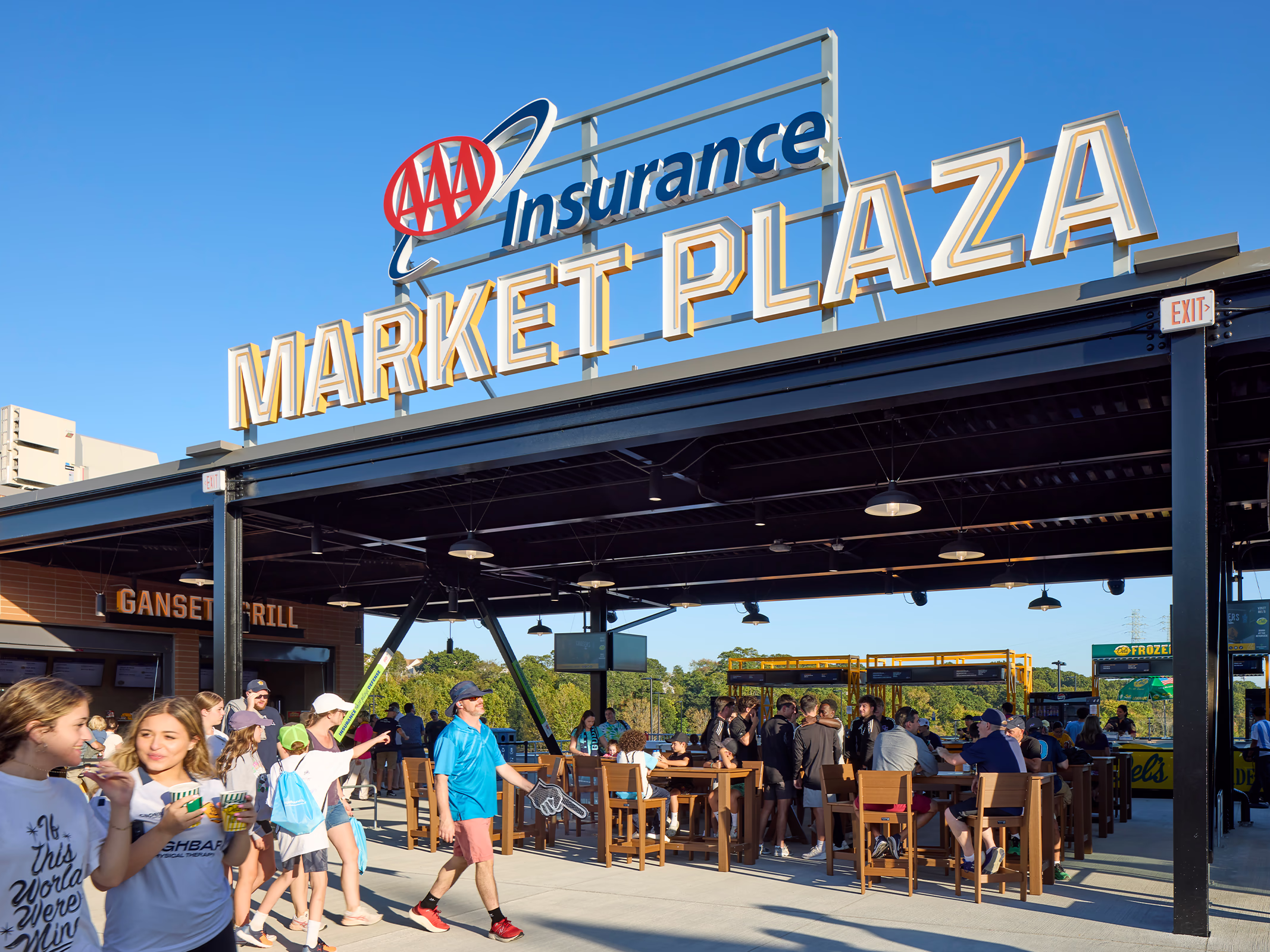 A large rooftop Market Plaza sign crowns the open-air food and beverage terrace at Centreville Bank Stadium, where fans gather at communal tables.