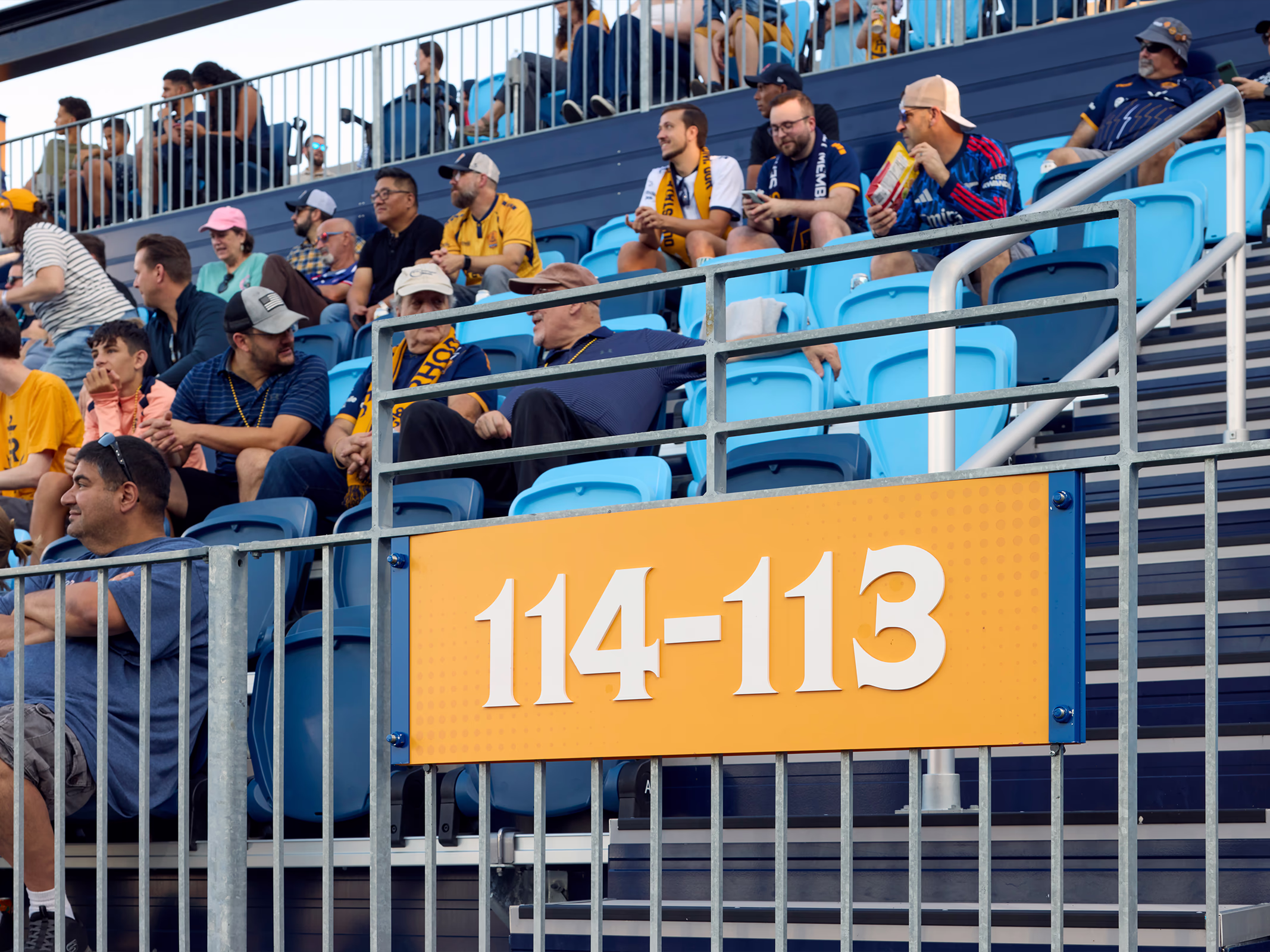 A yellow section marker reading 114-113 mounts to the railing at a seating bowl entry in Centreville Bank Stadium as fans settle into their seats.