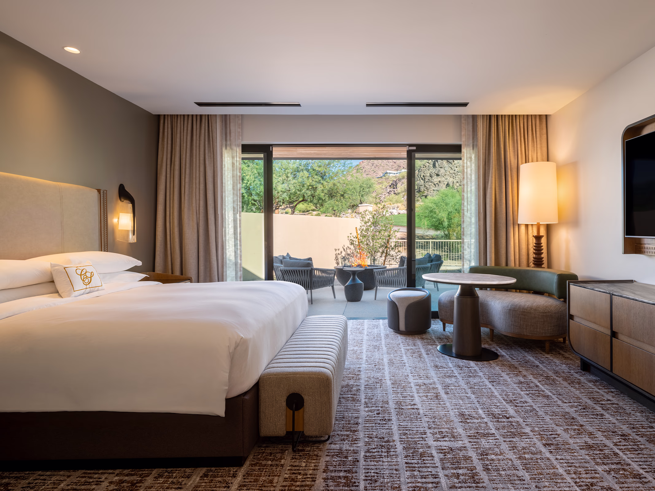 Bedroom in a Villas at Canyon Suites residence with a king bed, sitting area, and private terrace overlooking the Camelback Mountain foothills.