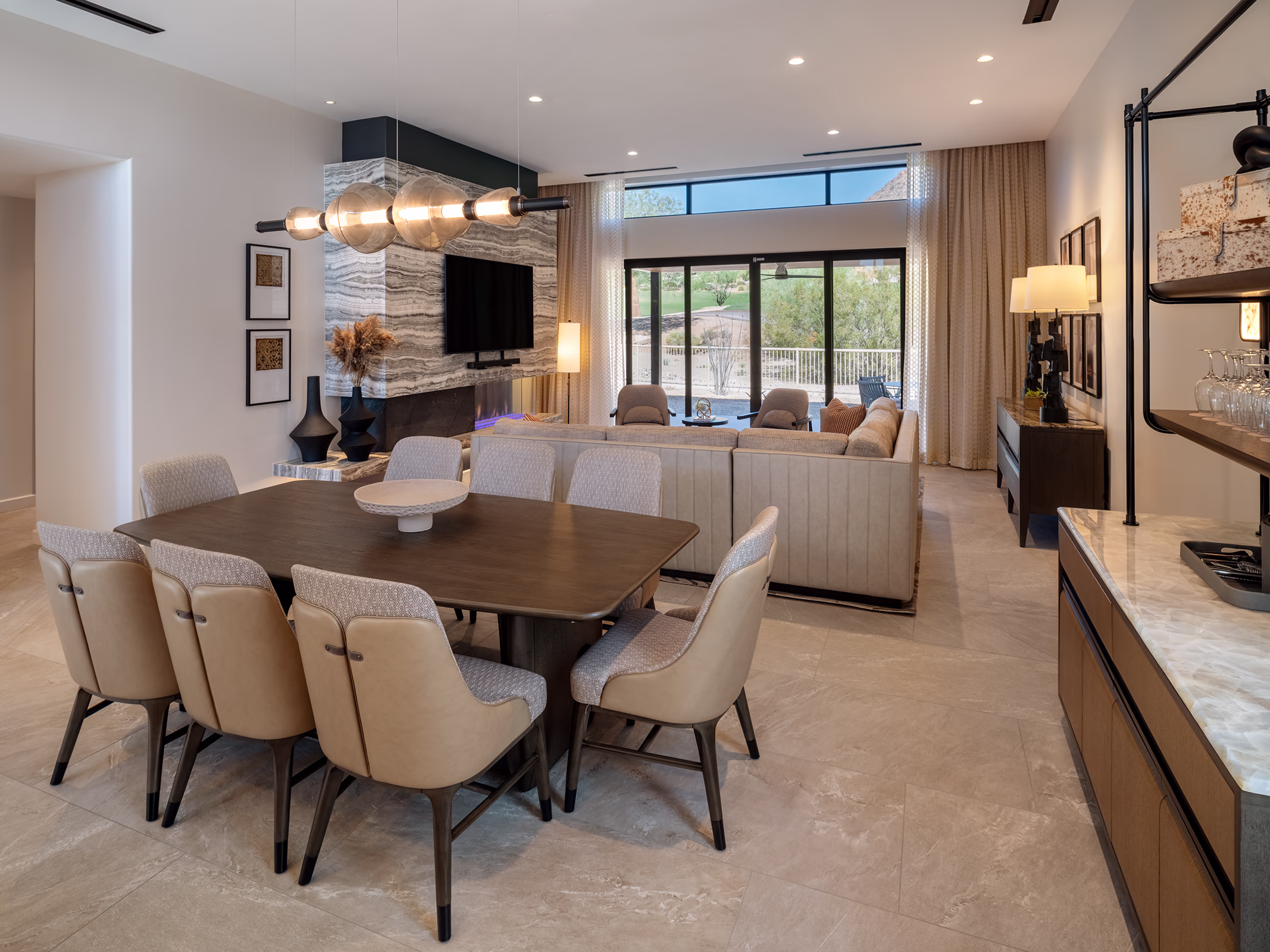 Living and dining area in a Villas at Canyon Suites residence with a stone fireplace, wet bar, and golf course views through floor-to-ceiling windows.