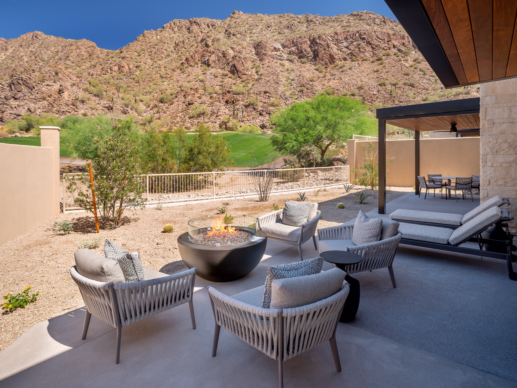 Private terrace at a Villas at Canyon Suites residence with a fire pit, outdoor seating, and covered dining area overlooking the golf course and mountains.