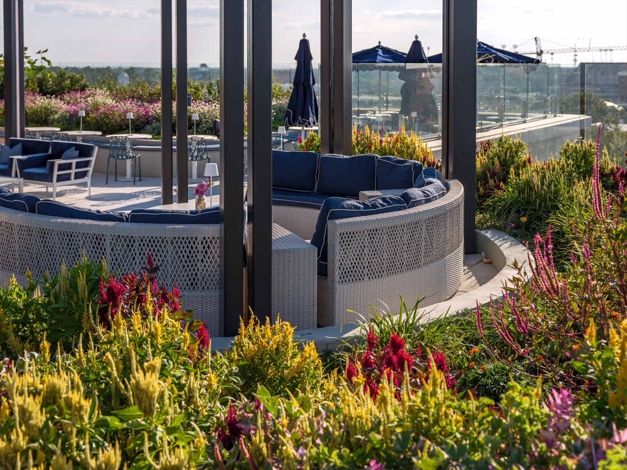 Circular lounge seating in the rooftop garden at The Laurel Hotel & Spa at Auburn University, framed by colorful celosia and amaranth planters.