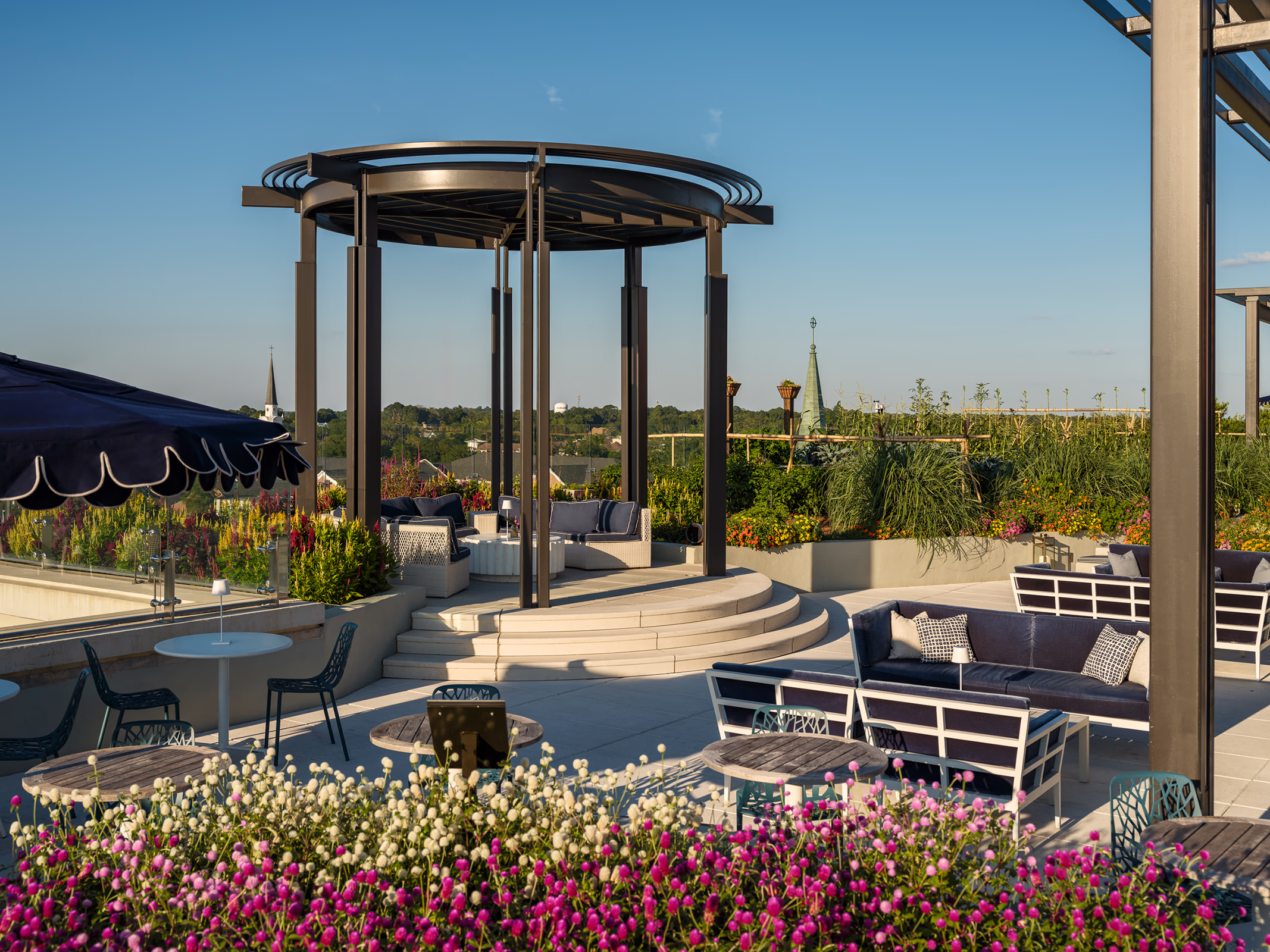Rooftop garden lounge at The Laurel Hotel & Spa at Auburn University, with a round pergola, outdoor seating, and flowering planters overlooking the town.